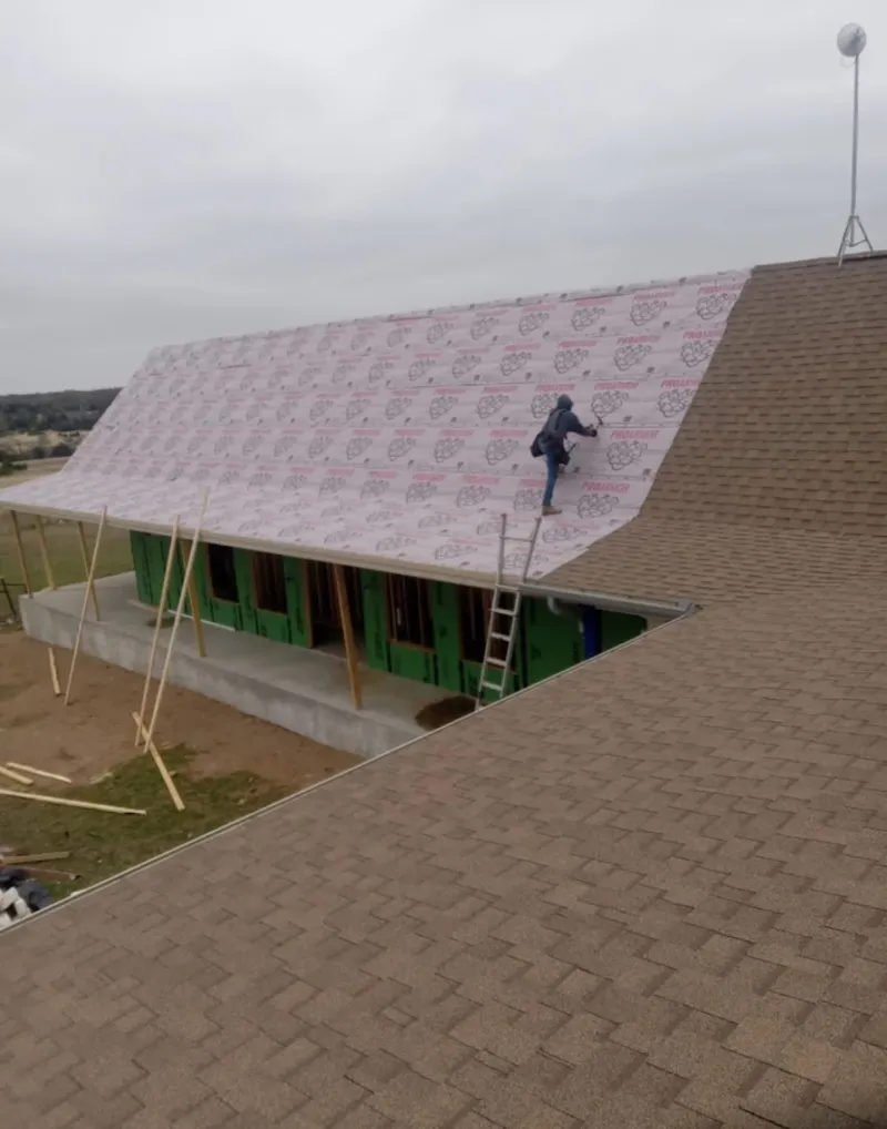 Worker preparing underlayment for a metal roof installation in New Whiteland